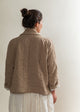 Person wearing a beige quilted jacket against a plain background