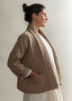 Woman wearing a brown quilted jacket against a plain background