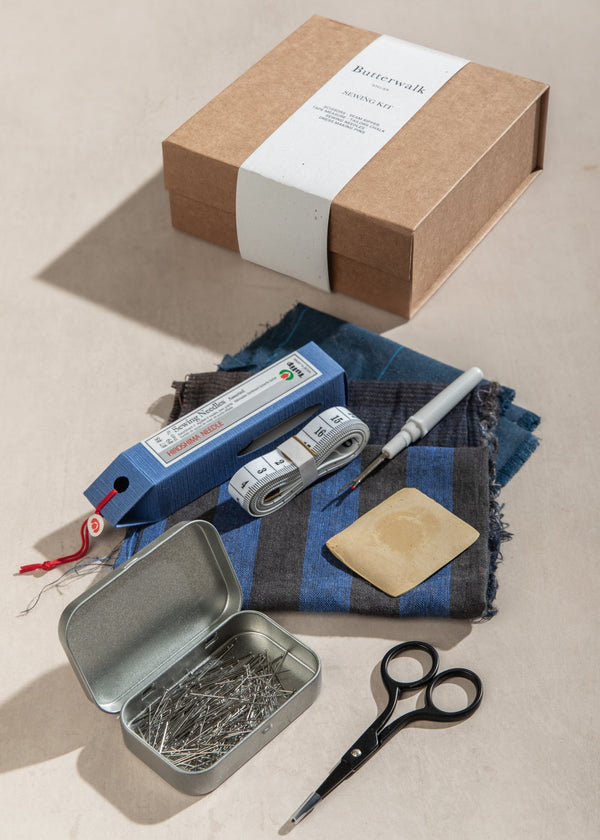 Crafting kit with box, scissors, and other tools on a beige surface