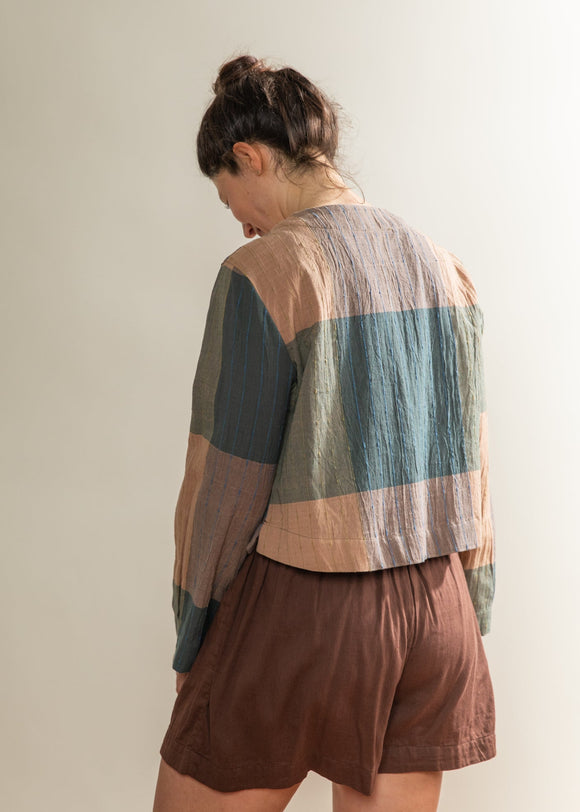 Person wearing a colorful striped shirt and brown shorts against a plain background