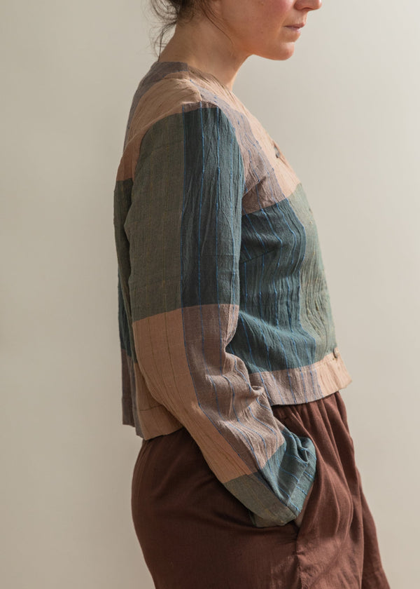Person wearing a colorful striped shirt and brown shorts against a plain background