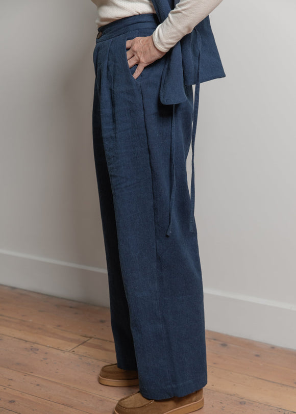 Person wearing a blue suit with a white shirt and brown shoes on a wooden floor.