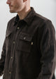 Man wearing a brown corduroy jacket on a plain background