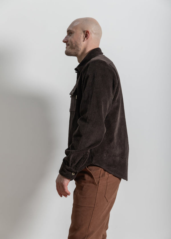 Man wearing a brown jacket and pants against a white background