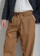 Brown pleated pants worn by a person against a neutral background