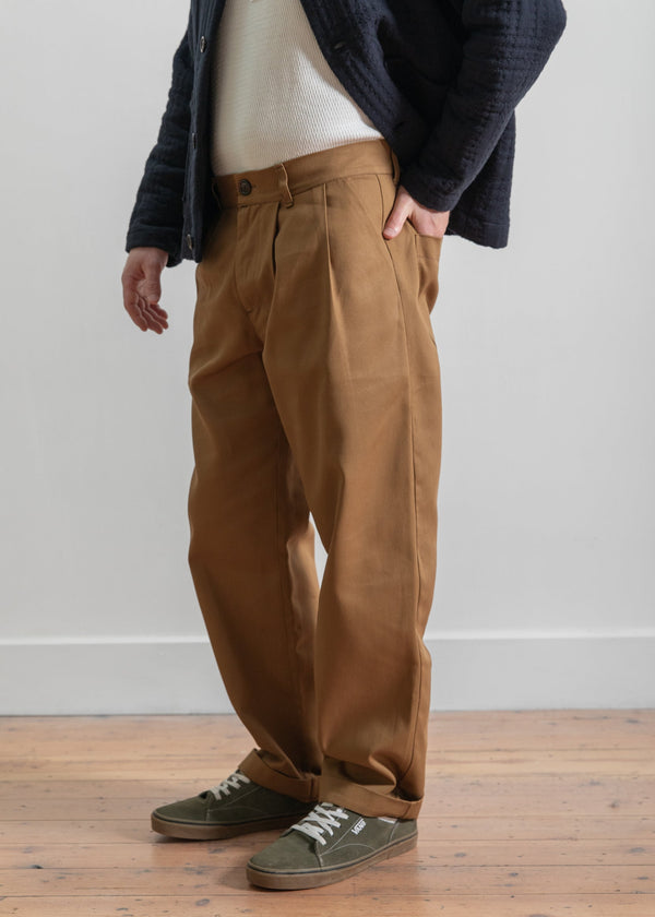 Person wearing brown pants and a dark jacket on a wooden floor.