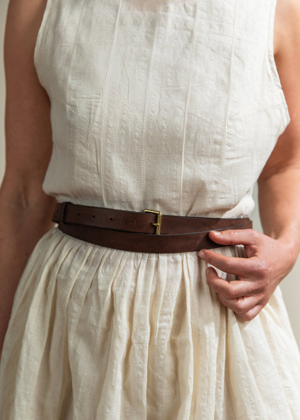 Person wearing a beige dress with a brown belt
