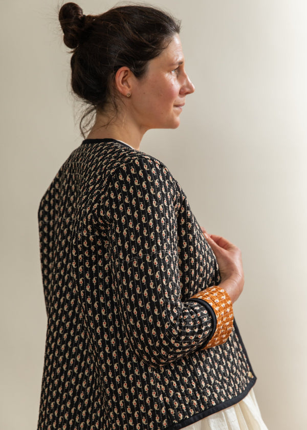 Woman wearing a black patterned jacket against a plain background