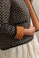 Person wearing a patterned jacket with a white skirt