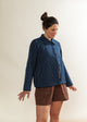 Woman wearing a blue pinstripe jacket and brown shorts against a white background
