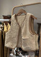 Beige fleece vest on a hanger with a blurred clothing store background