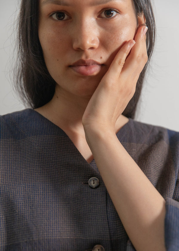 Woman wearing a dark brown button-up shirt against a plain background