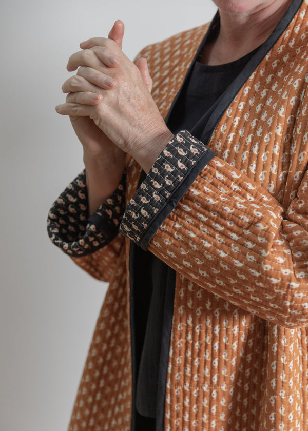 Person wearing a patterned robe with a neutral background