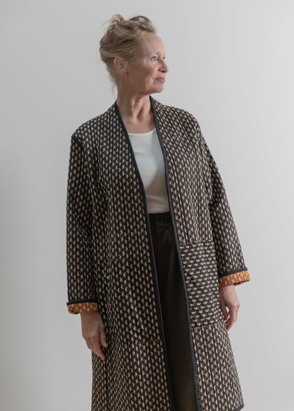 Woman wearing a patterned coat against a plain background