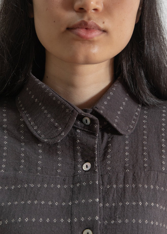 Close-up of a person wearing a dark gray textured shirt with a collar.