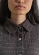 Close-up of a person wearing a dark gray textured shirt with a collar.