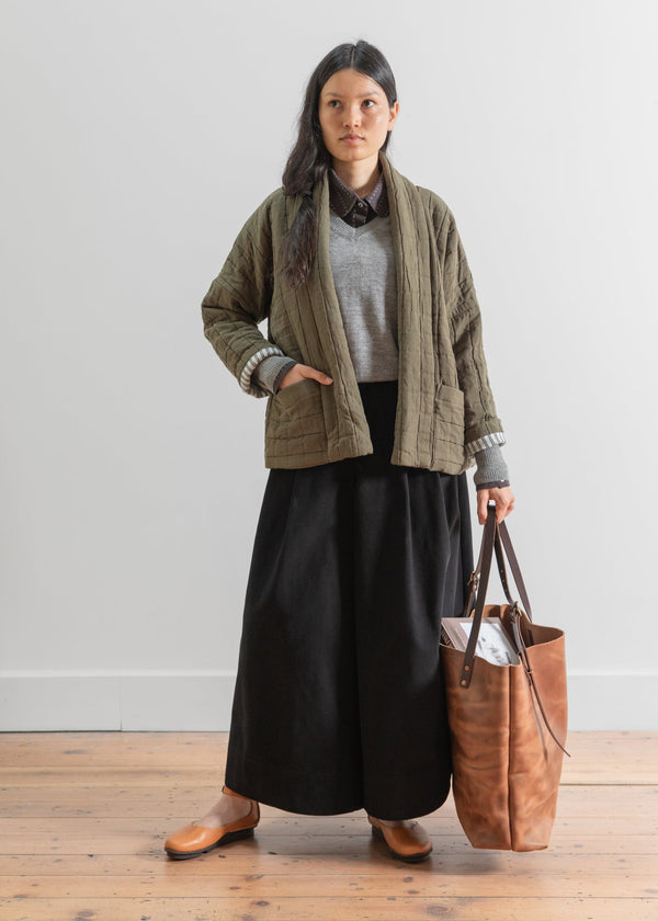 Woman holding a brown leather bag against a white background