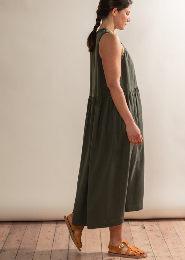 Woman wearing a green dress standing against a plain background