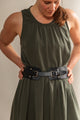 Woman wearing a green dress with a black belt against a plain background