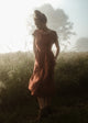 Woman in a dress standing in a field with a soft focus background