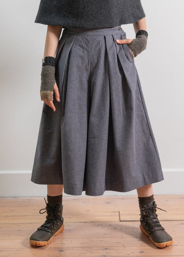 Person wearing a gray skirt with a plain background