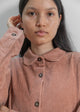 Person wearing a brown corduroy shirt against a plain background
