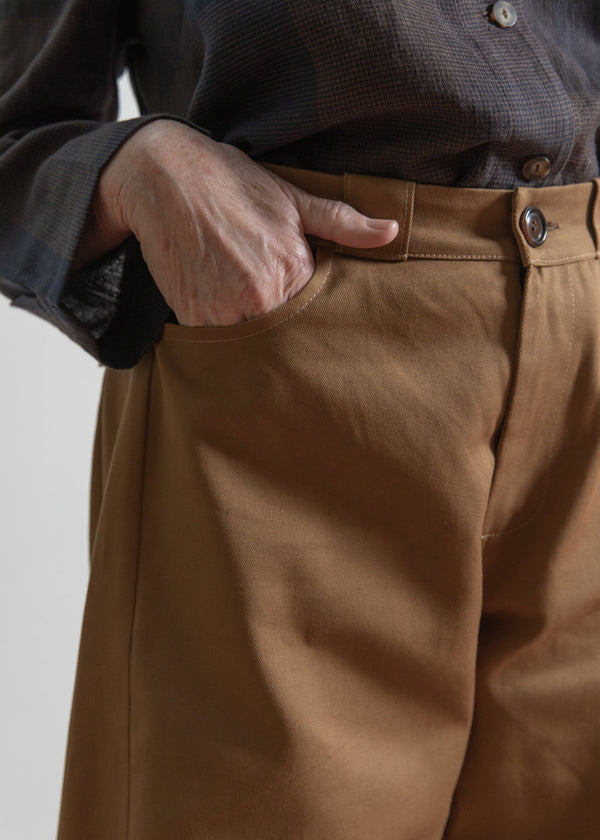 Brown pants with a person's hand in the pocket against a neutral background