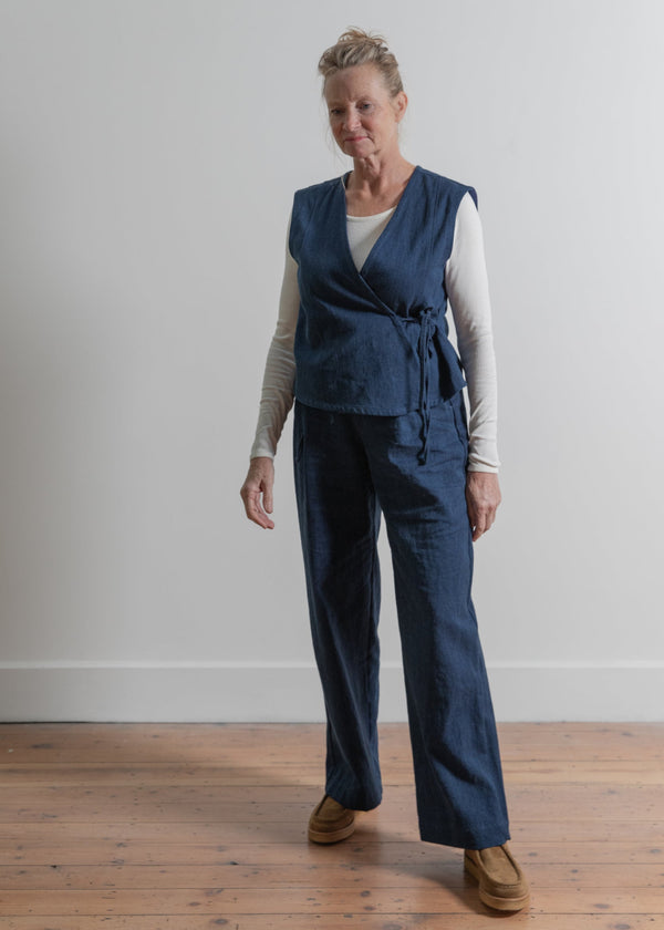 Woman wearing a blue vest and pants set on a plain background