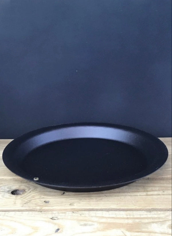Black round pan on a wooden surface with a dark blue background
