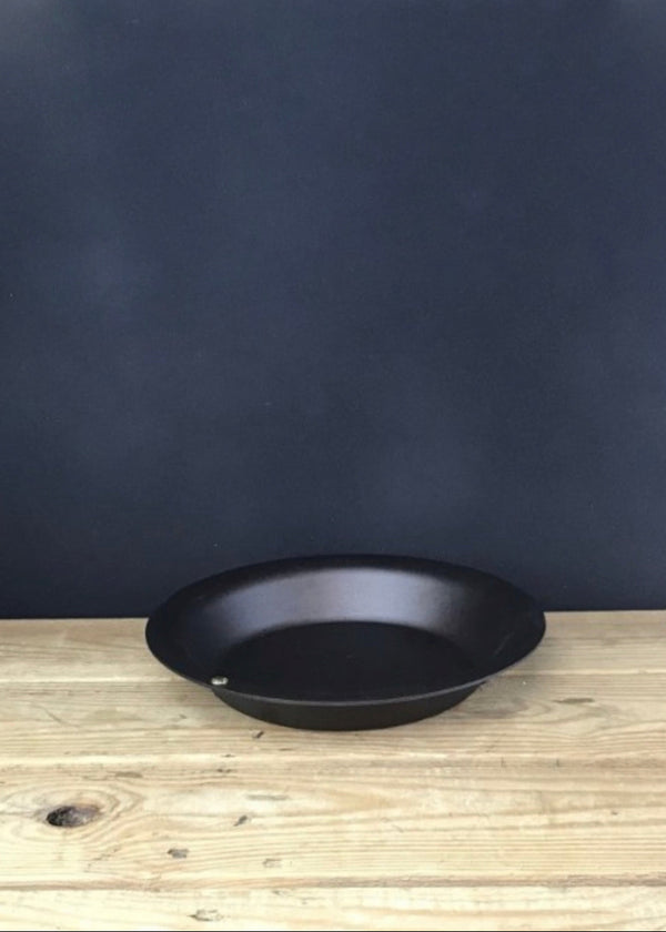 Black frying pan on a wooden surface with a dark blue background