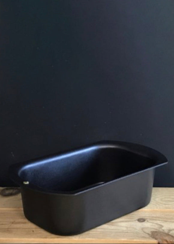 Black loaf pan on a wooden surface with a dark gray wall background