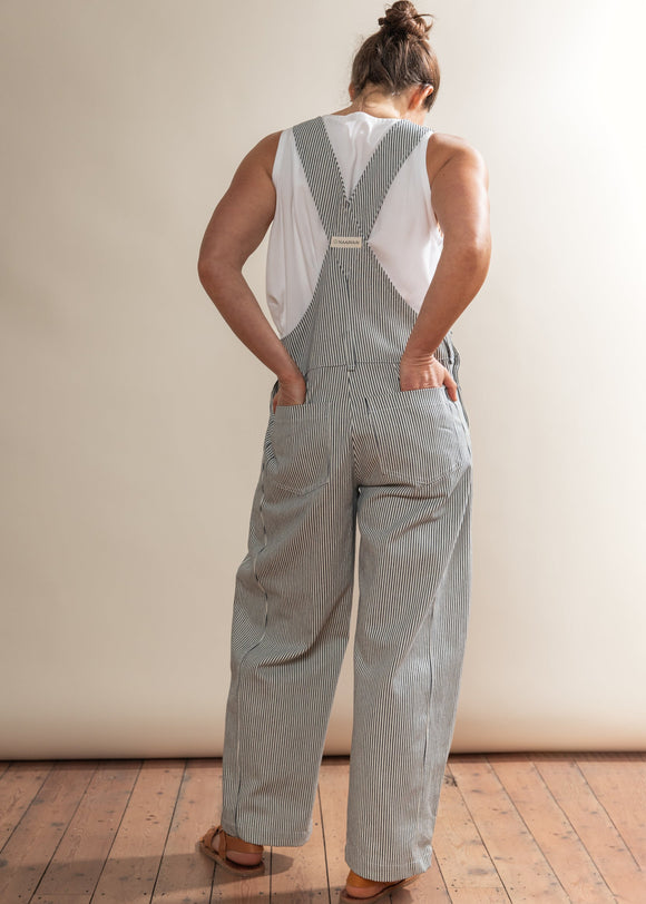 Person wearing a gray checkered jumpsuit with suspenders against a plain background