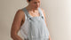 Woman wearing a gray striped overalls against a beige background