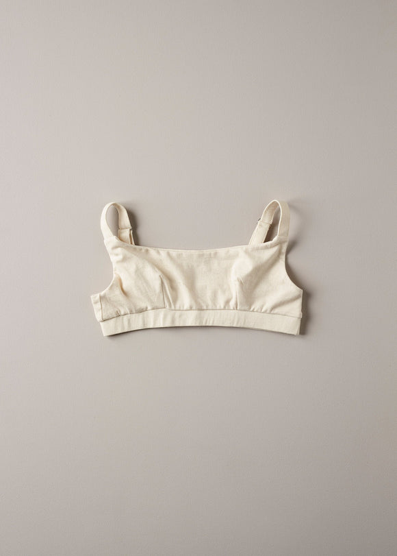 A beige organic cotton full crop top with covered adjustable straps and underband, displayed against a neutral background.
