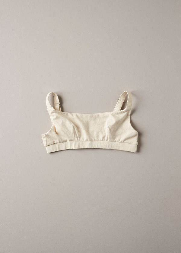 A beige organic cotton full crop top with covered adjustable straps and underband, displayed against a neutral background.