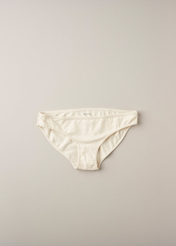A pair of low waist knickers in a natural beige color, laid flat on a plain background.