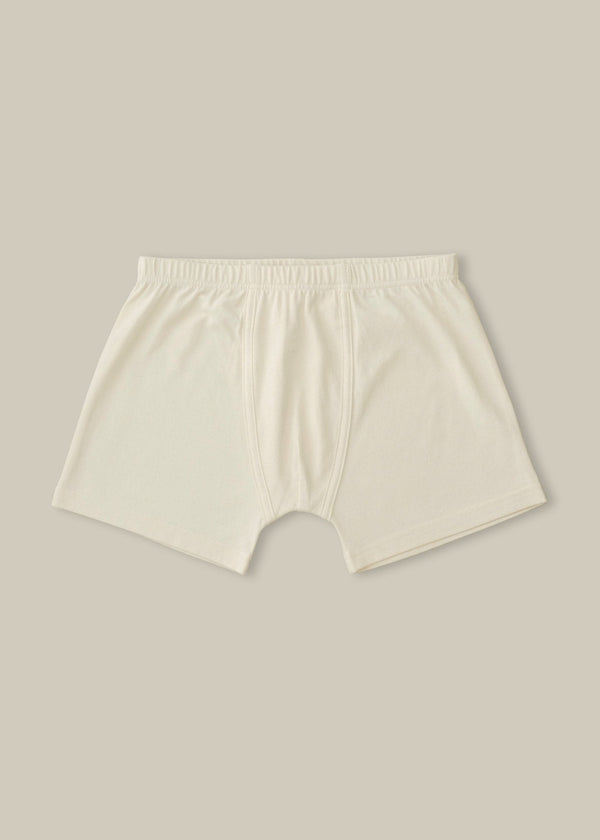 A pair of beige, organic cotton jersey trunk shorts with a slim fitting leg and enclosed elastic waistband.