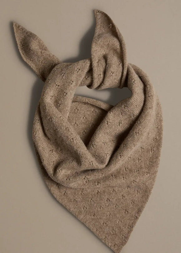 Beige knitted triangle scarf on a beige background