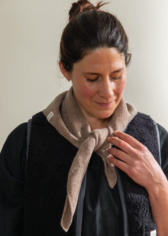 Woman wearing a beige scarf with a neutral background