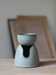 Gray ceramic oil burner on a wooden surface with a neutral background