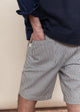 Person wearing navy shirt and striped shorts with a neutral background
