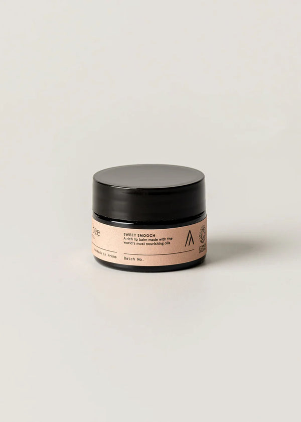 Cosmetic jar with black lid and pink label on a light beige background