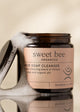 Jar of sweet bee Organics Black Soap Cleanser with a sponge and soap suds on a beige background