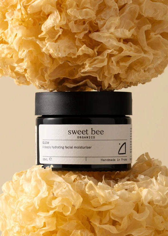 Jar of 'sweet bee' skincare product surrounded by natural sponge-like material on a beige background