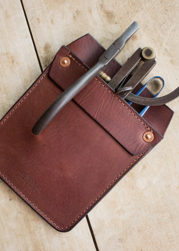 Brown leather multi-tool pouch with tools on a beige surface