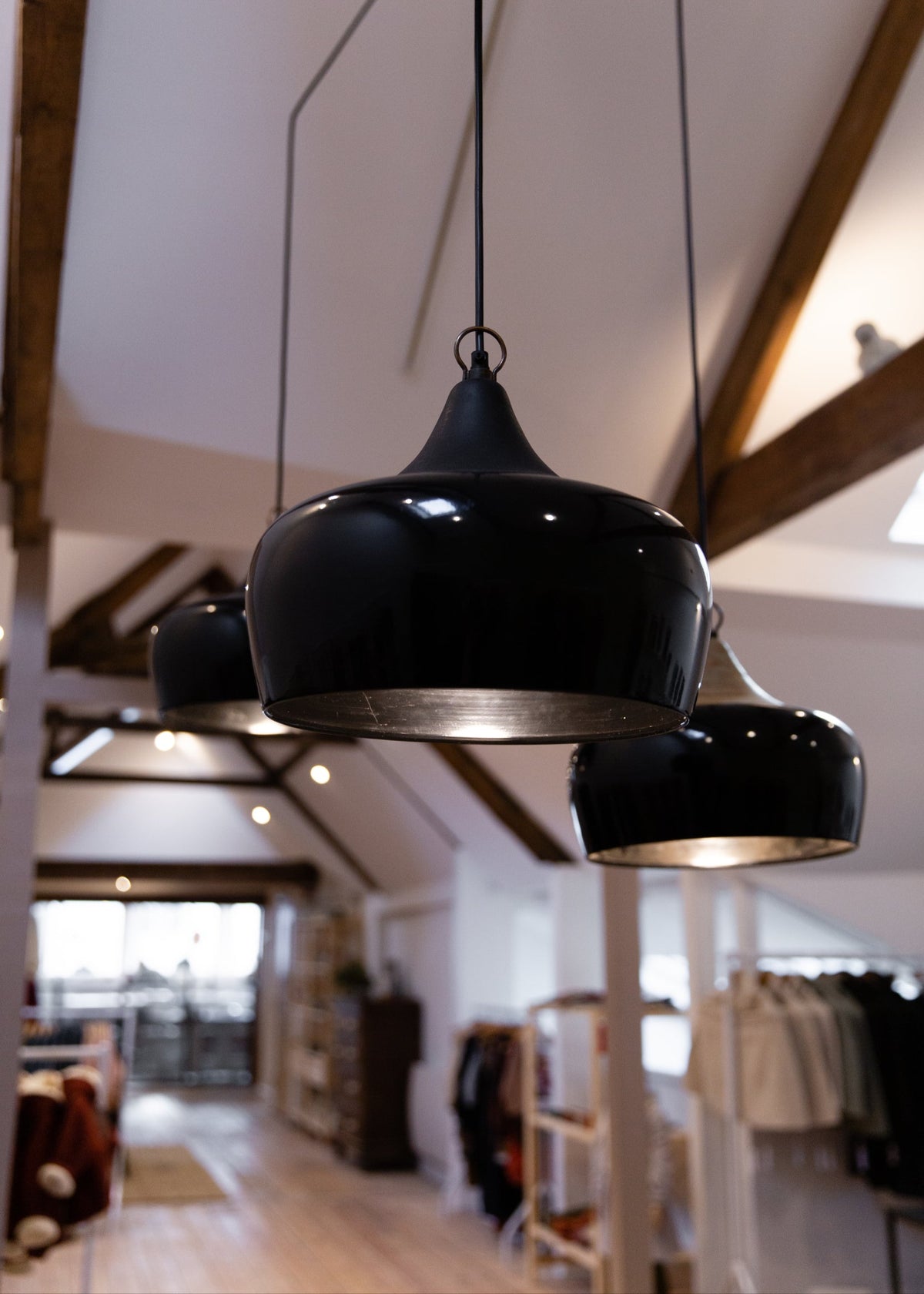 Black pendant lights hanging in a room with wooden beams and blurred background