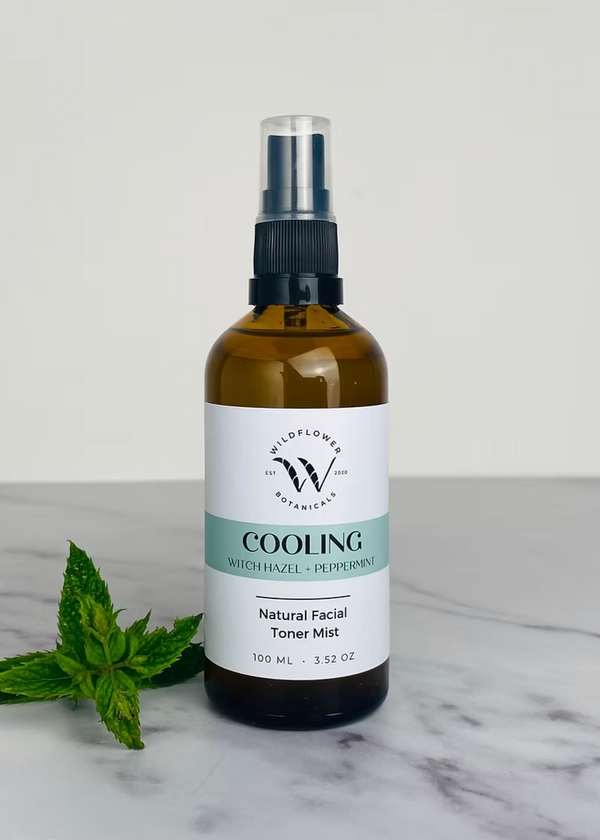 A bottle of facial toner mist labeled 'SOOTHING' with a spray nozzle, surrounded by a few sprigs of dried lavender on a marble surface.