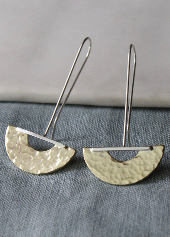 A pair of silver drop earrings with a textured finish, displayed against a grey background.