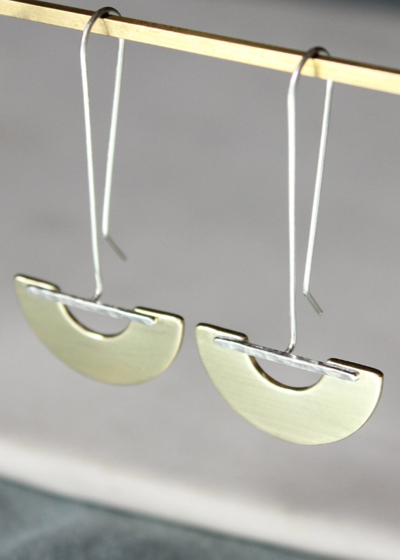 Pair of silver half-circle earrings on a gray background