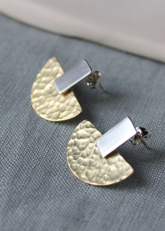 Pair of silver earrings with textured half-circle design on a gray surface